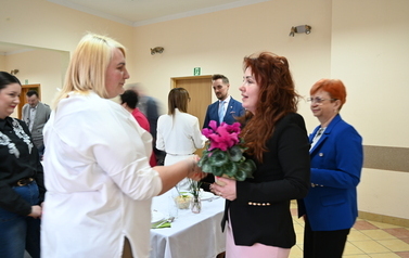 widzimy panią przekazującą pani kwiatka doniczkowego