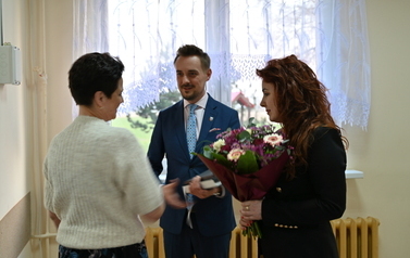 widzimy pana i panią stojącą z bukietem kwiat&oacute;w na przeciwko drugiej pani