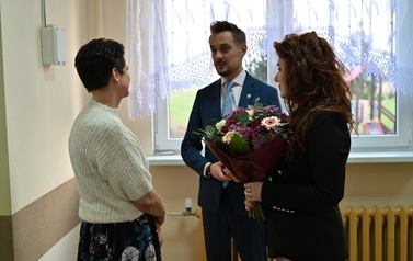 widzimy pana i panią stojącą z bukietem kwiat&oacute;w na przeciwko drugiej pani