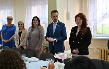 widzimy stojące osoby przy stole 