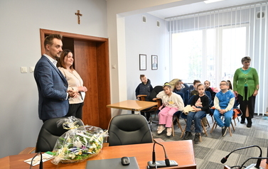 widzimy siedzące dzieci oraz panią i pana 