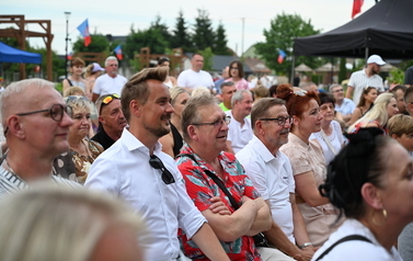 Publiczność siedząca i stojąca przed sceną podczas plenerowego wydarzenia