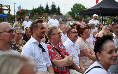 Publiczność siedząca i stojąca przed sceną podczas plenerowego wydarzenia