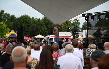 Ludzie siedzący na ławkach i patrzący na osobe występującą na scenie