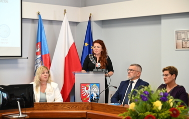 Siedzący radni pośrodku stoi Przewodnicząca Rady Gminy