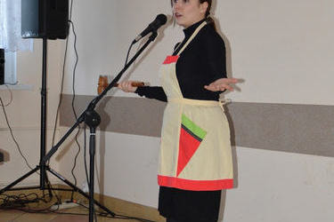 Na zdjęciu widać młodą kobietę z mikrofonem, śpiewa piosenkę. 