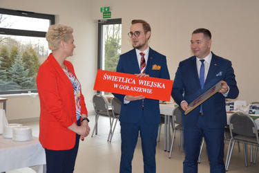 Na zdjęciu w&oacute;jt przekazuje pani sołtys tablicę informacyjną świetlicy wiejskiej w Gołaszewie.