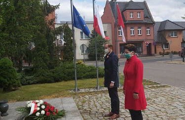 Na zdjęciu znajduje się W&oacute;jt Gminy Mieścisko Przemysław Renn wraz z Przewodniczącą Rady Gminy Mieścisko Panią Kamilą Mazurek. Stoją w skupieniu przed pomnikiem, na kt&oacute;ry przed chwilą złożyli wieniec z kwiat&oacute;w.