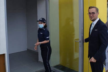 Na zdjęciu widać jak pani komendant policji otwiera drzwi do siedziby dzielnicowych.