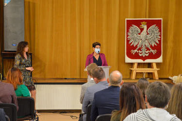 Na zdjęciu widac Przewodniczącą Rady Gminy - kobieta w czarnej bluzce i fuksjowym żakiecie wygłasza przemowę przy m&oacute;wnicy. Ma ona kr&oacute;tkie ciemne włosy
