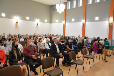 Zdjęcie przedstawia zgomadzonych stypendyst&oacute;w wraz z rodzicami. Wszyscy siedzą na krzesłach na sali widowiskowej w Domu Kultury