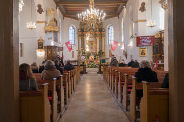 Na zdjęciu widać wnętrze kościoła, w ławkach siedzi kilka os&oacute;b, ksiądz odprawia mszę. 