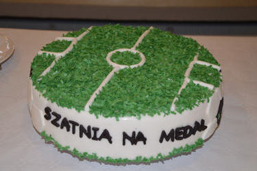 Na zdjęciu widać okrągły tort w kształcie boiska  -zielony z białymi dodatkami, z napisem Szatnia na medal.