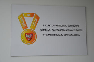 Na zdjęciu znajduje się tabliczka z napisem "Projekt dofinansowano ze środk&oacute;w samorządu Wojew&oacute;dztwa Wielkopolskiego w ramach programu Szatnia na medal"