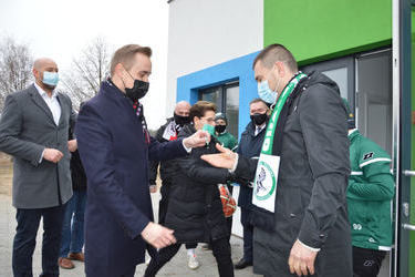 Na zdjęciu w&oacute;jt wręcza klucz do szatni prezesowi klubu Sok&oacute;ł - mężczyźnie w ciemnej kurtce z szalikiem Sokoła.