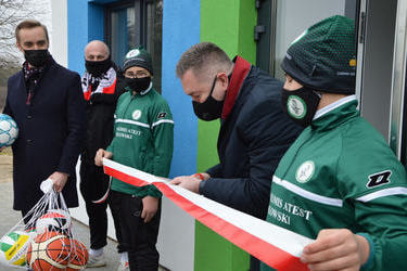 Na zdjęciu mężczyzna w granatowym płaszczu-wicemarszałek Jacek Bogusławski przecina wstęgę.