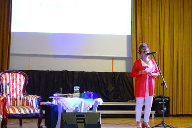 Na zdjęciu widać jubilatkę odczytującą przemowę. Ubrana jest w białe spodnie i czerwoną tunikę