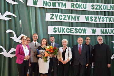 Na zdjęcfiu widać gości zaproszonych na uroczystość rozpoczęcia roku szkolnego 2021/2022. Wszyscy są w odświętnych strojach. Pani Pałczyńska trzyma w rękach kwiaty oraz nominację
