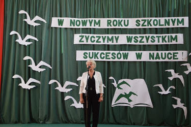 Na zdjęciu widać przemawiającą odchodzącą Panią Dyrektor Jadwigę Soczkę. Ubrana jest w strr&oacute;j uroczysty.