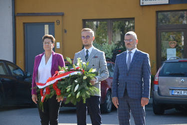 Na zdjęciu widać Pana W&oacute;jta w towarzystwie Pani Przewodniczącej Rady Gminy i Radnego . Pan W&oacute;jt trzyma w rękach wiązankę z biało czerwonych kwiat&oacute;w.