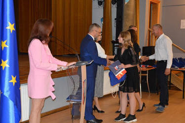 Na zdjęciu widać jak dziewczynka otrzymła stypendium naukowe od W&oacute;jta Gminy Mieścisko. Przyjmuje teraz gratulacje od radnego.