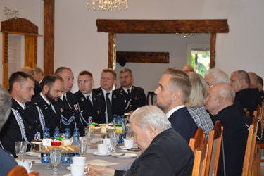 Przy stole siedzą w mundurach galowych strażacy z OSP, Pan W&oacute;jt, Pani Skarbnik i Ksiądz Kanonik. 