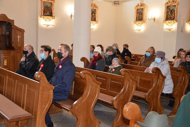 Na zdjęciu widać ludzi siedzących w ławkach kościoła.