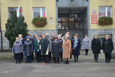 Na zdjęciu widać grupę ludzi - ch&oacute;r. Obok stoją dwie kobiety ubrane na czarno - dyrektorzy szkoły i przedszkola.