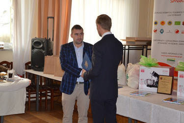 Na zdjęciu w&oacute;jt wręcza podziękowanie młodemu mężczyźnie ubranemu w jasną koszulę i marynarkę w kratę. Jest on przedstawicielem KOWRu z Poznania.