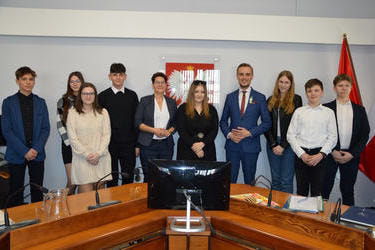 Zdjęcie przedstawia wszystkich młodych radnych wraz z W&oacute;jtem Gminy oraz przewodniczącą Rady Gminy. Wszyscy są uśmiechnięci.