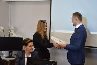 Na zdjęciu w&oacute;jt wręcza dokumenty i gratulacje młodej radnej. Jest to dziewczyna w długich, jasnych włosach,ciemnej sukience.