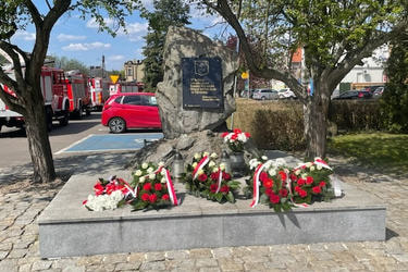 Zdjęcie przedstawia pomnik na Placu Powstańc&oacute;w Wielkopolskich na kt&oacute;rym znajdują się biało-czerwone wiązanki kwiat&oacute;w.