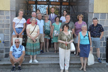 Zdjęcie grupowe na schodach przed Urzędem Gminy w Mieścisku z W&oacute;jtem. Jeden mężczyzna z Holandii siedzi na schodach. Wszyscy są uśmiechnięci.