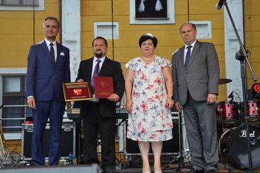 Zdjęcie przedstawia na scenie od lewej storny w&oacute;jta Gminy Mieścisko, starostę dożynek trzymającego w rękach odznaczenie Herbu Powiatu, starościne dożynek, Starostę Powiatowego.