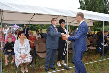 Na zdjęciu widać w&oacute;jta rozdającego chleb dożynkowy gościom.