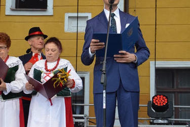 Na zdjęciu widać w&oacute;jta Gminy Mieścisko. Stoi na scenie i wygłasza przem&oacute;wienie. Ubrany jest w granatowy garnitur.