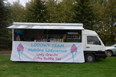 Zdjęcie przedstawia mobilne stanowisko z lodami i goframi.