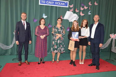 Zdjęcie przedstawia od lewej strony w&oacute;jta, panią dyrektor w okularach i śliwkowej sukni, następnie radna w kwiecistej sukni, obok stypendystka w galowym stroju. obok niej rodzice.