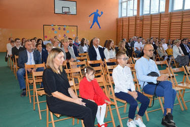 Zdjęcie przedstawia stypendyst&oacute;w wraz z rodzicami siedzących na drewnianych krzesłach.