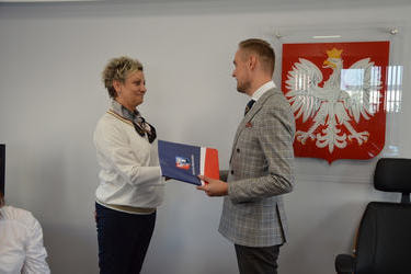 Na zdjęciu w&oacute;jt wręcza nagrodę nauczycielce. Kobieta w jasnych włosach, ubrana w jasną bluzkę i ciemne spodnie, ma na szyi apaszkę.