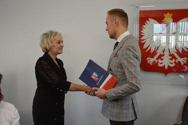 Na zdjęciu w&oacute;jt wręcza nagrodę nauczycielce. Kobieta ma kr&oacute;tkie blond włosy, ubrana jest w czarną sukienkę.