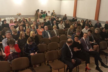 Na zdjęciu widać gości przybyłych na galę. Siedzą na krzesłach ustaiwonych w rzędy na sali widowiskowej.