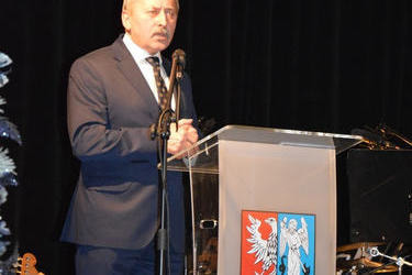 Na zdjęciu widać mężczyznę stającego za m&oacute;wnicą. Ubrany jest w ciemny garnitur.