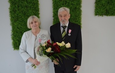 Zdjęcie przedstawia parę jubilat&oacute;w. Kobieta w jasnych włosach do uszu. Ma jasna garsonkę. Mężczyzna w siwych włosach z brodą. Ma czarny garnitur.
