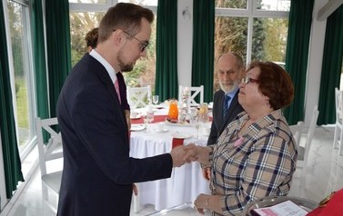 Na zdjęciu w&oacute;jt gratuluje kobiecie. Obok stoi jej mąż. Wyglądają na zadowolonych.