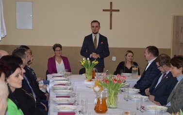 Zdjęcie przedstawia przemawiającego w&oacute;jta. Obok siedzi przewodnicząca rady oraz urzędniczka.