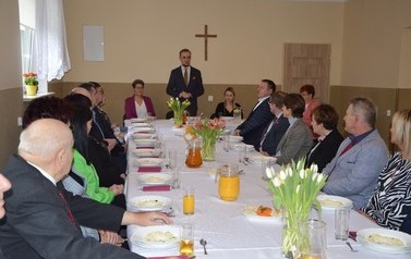 Zdjęcie przedstawia siedzących przy stole sołtys&oacute;w. W oddali stoi w&oacute;jt i wygłasza przemowę.