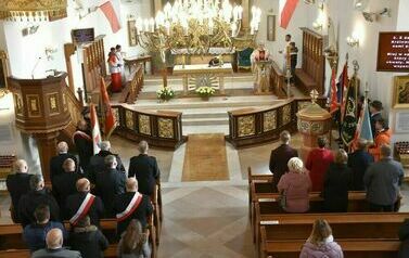 Zdjęcie zrobione z balknu kościoła przedstawia widok na cały prz&oacute;d kościoła. Zgromadzeni stoją przodem do przemawiającego księdza. 