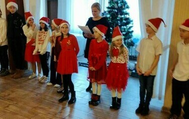 Grupa dzieci w czapkach Świętego Mikołaja.