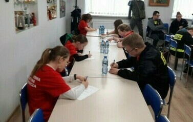 Dzieci rozwiazujace test na kartkach papieru siedzące przy stole